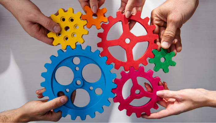 Hands holding 6 multicoloured spokes being fitted together.