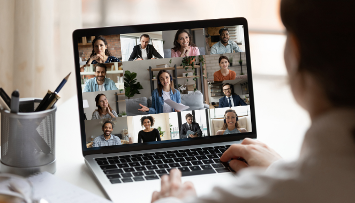 Many people on a laptop screen with someone looking at it.