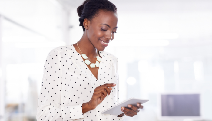 A business woman smiling while holding a tablet.